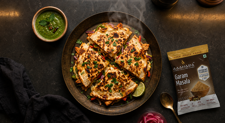 Tandoori paneer quesadilla wedges on a dark platter with mint chutney, pickled onions, lime and Aaahara Garam Masala
